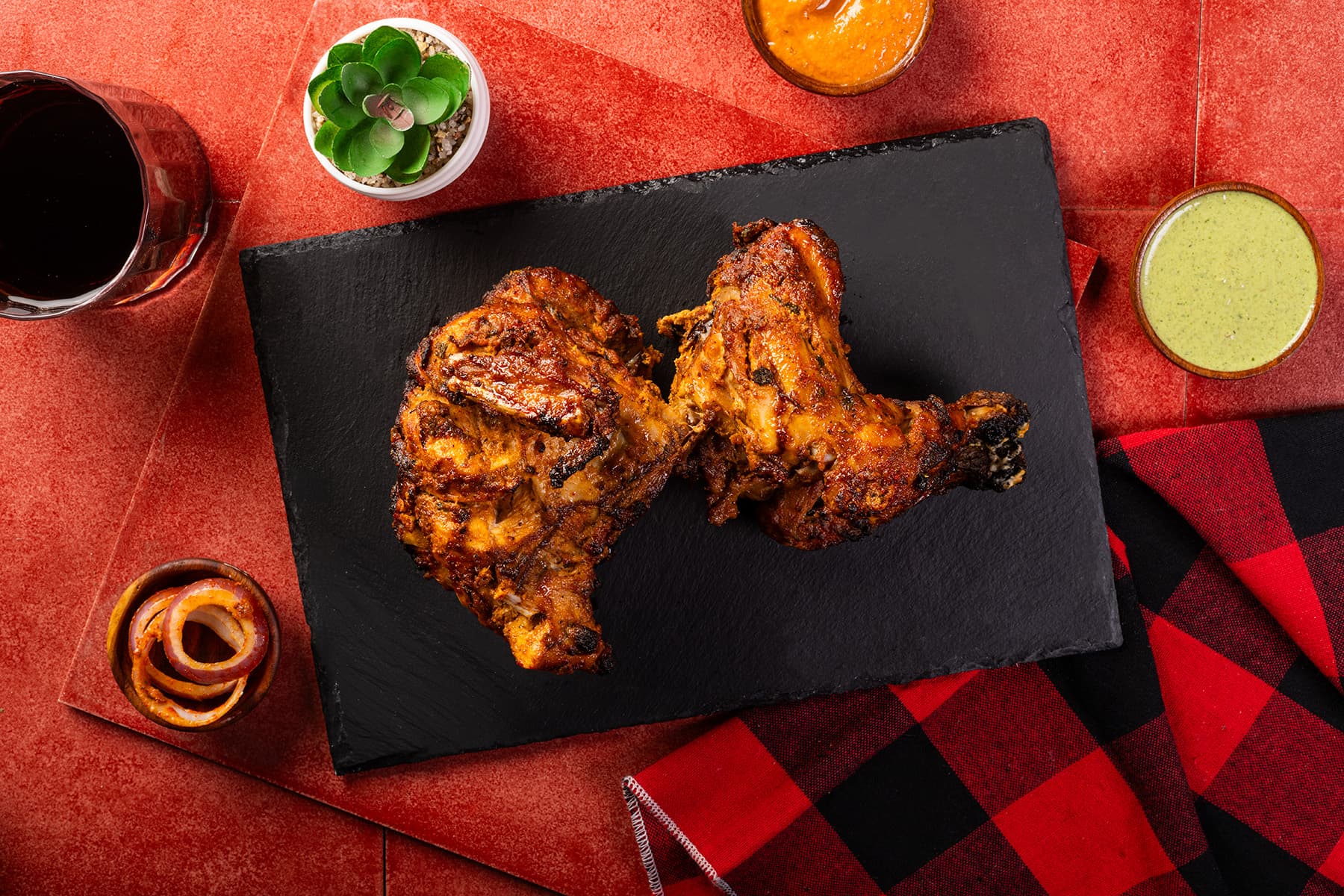 MK's tandoori chicken on a slate board with mint chutney and pickled onions